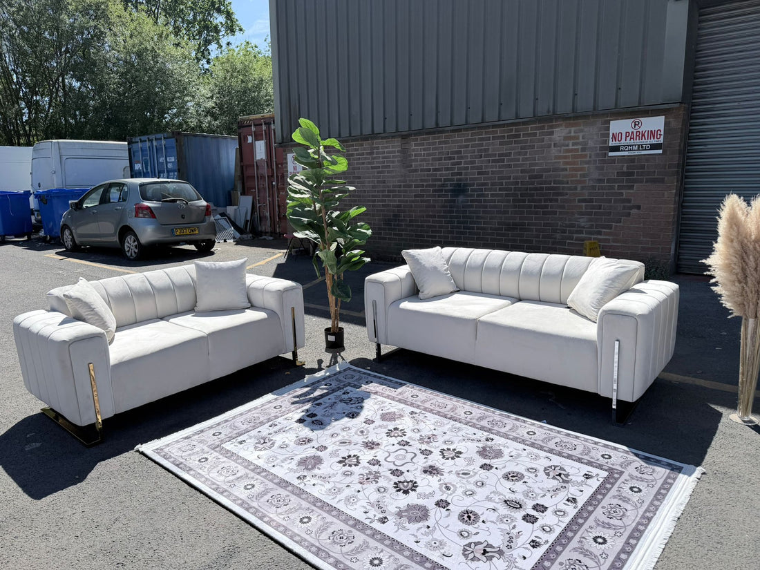 Two white sofas on a patterned rug in an outdoor setting with a building and car in the background.